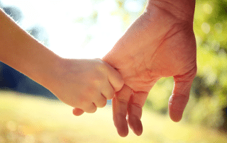 Close up of the hands of parent and child holding hands to represent healing avoidant attachment